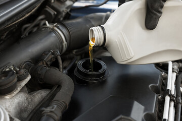 Man pouring motor oil into car engine, closeup