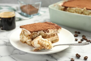 Piece of tasty tiramisu on white marble table, closeup