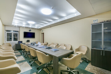 Spacious meeting room in a modern office. A long table and comfortable beige chairs..