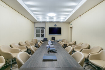 Large office room for negotiations and meetings. A TV on the wall, a long table and comfortable chairs..