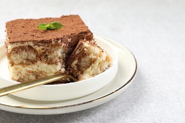Delicious tiramisu with mint on light table, closeup