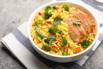 Tasty rice with vegetables and chicken on grey table, closeup