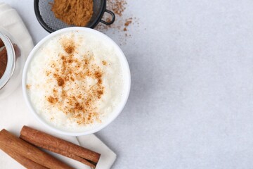 Delicious rice pudding with cinnamon on light table, flat lay. Space for text