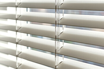 Light filtering through white horizontal blinds in a bright room