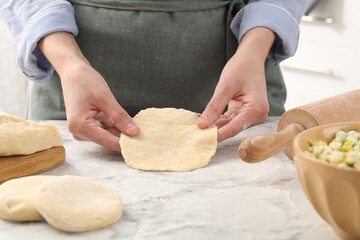 Woman making pirozhki (stuffed pastry pies) at white marble table indoors, closeup