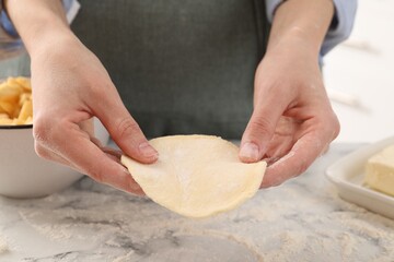 Woman making pirozhki (stuffed pastry pies) at white marble table indoors, closeup