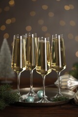 Champagne in glasses and Christmas decor on wooden table against blurred lights. Bokeh effect