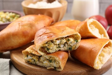 Delicious pirozhki (stuffed pastry pies) and ingredients on table, closeup