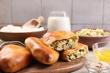Delicious pirozhki (stuffed pastry pies) and ingredients on grey table, closeup
