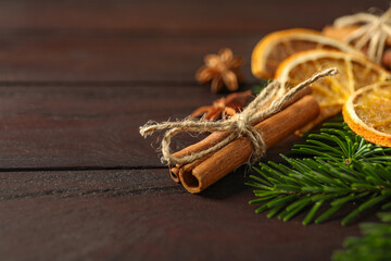 Different spices, dried orange slices and fir tree branches on wooden table, closeup with space for text. Christmas season