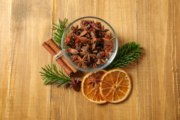 Different spices, dried orange slices and fir tree branches on wooden table, flat lay. Christmas season