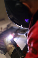 experto soldador trabajando en una soldadura de metal con mascara protectora y guantes