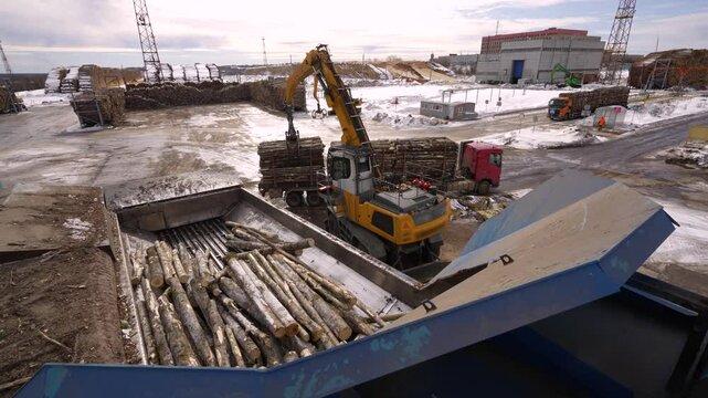 Manipulator crane unloads timber from a logging truck for processing. copter