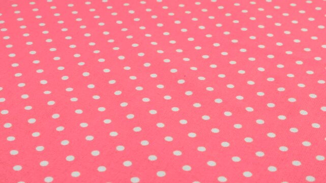 Close-up view of the taffy pink with white polka dots cotton fabric rotated on the display case. Textile background on the design theme, craft, handmade, patchwork, creativity theme.