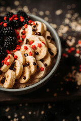 Oatmeal with red ripe blackberries and bananas in the bowl. Selective focus.