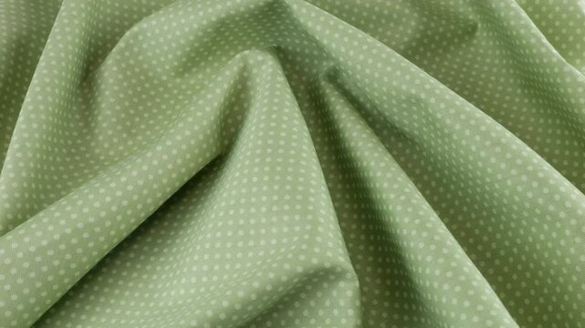 Top view of the soft folds of light green with white polka dots cotton fabric rotated on the display case. Textile background on the design theme, craft, handmade, patchwork, creativity theme.