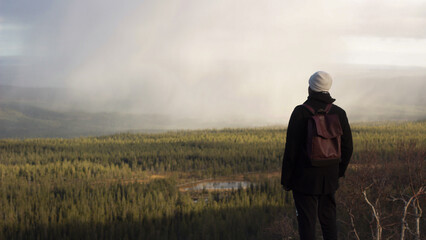 Man in dark clothes looks over mountain landscape, Sweden