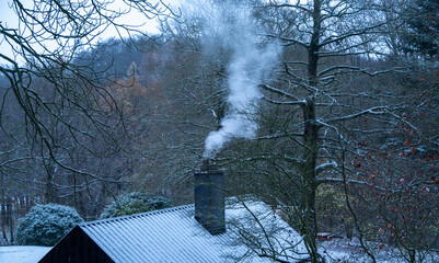 Rauch steigt aus dem Schornstein einer winterlich verschneiten Hütte