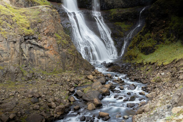 A stunning Icelandic waterfall cascading down rugged cliffs into a serene pool.