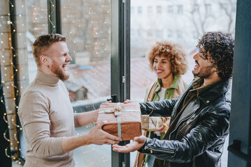 Man welcoming guests on holiday with gifts near door at home