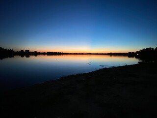 Beautiful summer sunset over a lake at night from the shore, reflections over the water, at Holmes Park in Lincoln, Nebraska, United States