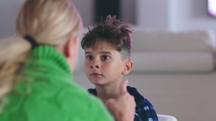 A mother firmly addressing her rebellious son, offering guidance and advice on proper behavior. They are seated in the living room during a serious moment of discipline and learning.