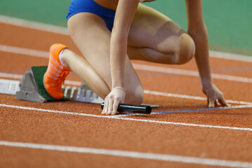 Runner preparing at starting blocks for a relay race during a track event