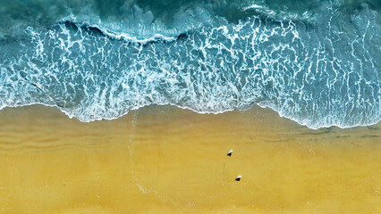 Aerial view of ocean waves meeting sandy beach. A breathtaking top-down aerial view of gentle ocean waves crashing onto a golden sandy beach.