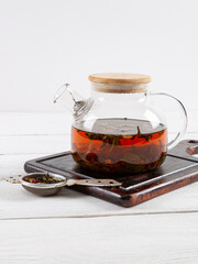 Teapot with tea on a white wooden background.