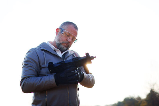Man with gray jacket shooting black rifle on a white background