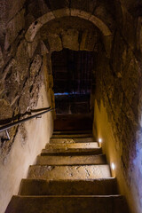 A dimly lit stone staircase descends into a mysterious underground passage © wundermann