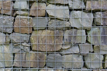 Beautiful natural stones laid out in a metal frame. Concept of natural fencing