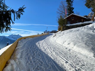 Fototapeta premium Winter snow idyll along the rural alpine road above the Lake Walen or Lake Walenstadt (Walensee) and in the Swiss Alps, Walenstadtberg - Canton of St. Gallen, Switzerland (Schweiz)