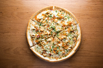 Creamy Seafood Pizza topped shrimp, squid and melted cheese served on wooden board isolated on table background top view of italian cousin