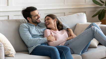 Obraz premium happy young husband and wife relaxing on comfortable sofa
