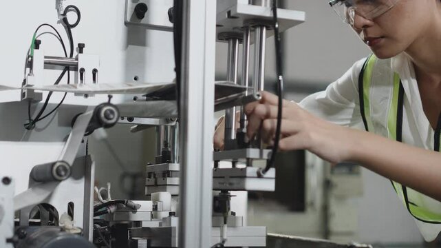 Front view of Maintenance Engineer working at assembly machine to repair, installing, analyzing, and testing in automated factory.
