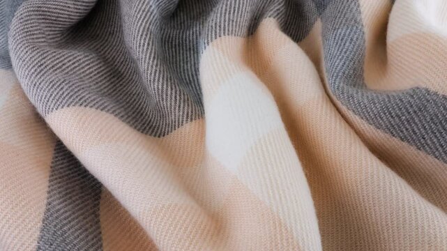 Top view of the soft folds of wool fabric in pastel gray-pink colors rotated on the display case. Textile background on cold weather, warm clothes, comfort, accessories and design theme.