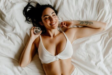 Naklejka premium Smiling young hispanic female relaxing on bed with crystal ball in hand