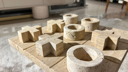 Close-up view of a tic-tac-toe board crafted from natural stone, featuring X and O pieces. The warm...