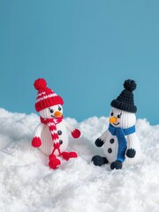 Knitted snowman toys sitting on fluffy snow against a blue backdrop, miniature