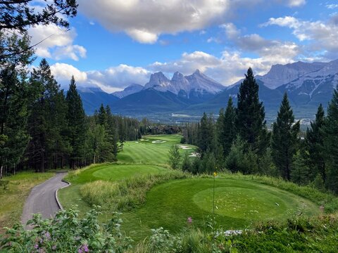 A beautiful view of a downhill par 4 surrounded by forests with the mountains in the background, in Canmore, Alberta, Canada