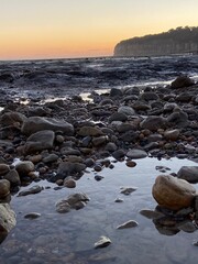 Pett Level Beach at Sunset. With pool of sea ocean water and rocks in foreground. Winchelsea Beach meets the cliffs a petrified forest visible at low tide, on the South coast of England East Sussex UK