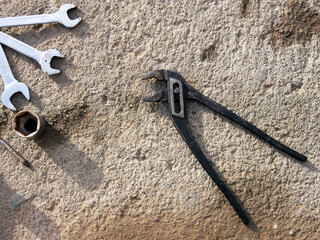 Tools: tongs, pliers, captive horn wrenches of various sizes on a gray concrete surface. Automotive mechanics tool, automotive repair, industry, engineering