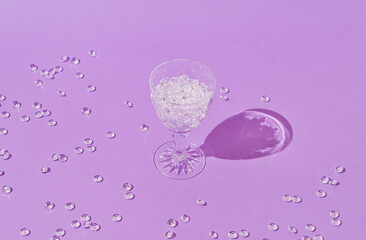 Creative trendy layout made with cocktail glass with diamonds on purple background. Minimal jewelry retro fashion party concept. Romantic drink idea. Light and shadows.