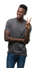 Young african american man wearing grey t-shirt smiling with happy face winking at the camera doing...