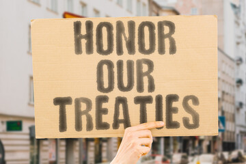 The phrase 'Honor our treaties' on a banner held by a person, agreements and commitments. Respect....