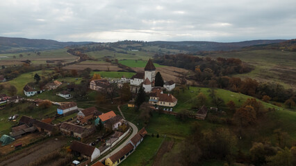 A stock photo of the Hosman Fortified Church in Romania during autumn showcases the beauty of this medieval structure amidst the vibrant colors of fall. 