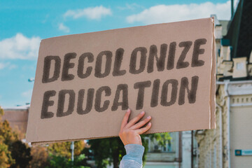 The phrase 'Decolonize education' on a banner held by a person. Educational inequality and systemic...