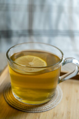 A cup of green tea with lemon on a cozy tablecloth, highlighting health and comfort.