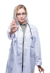 Young blonde doctor woman over isolated background doing stop sing with palm of the hand. Warning expression with negative and serious gesture on the face.